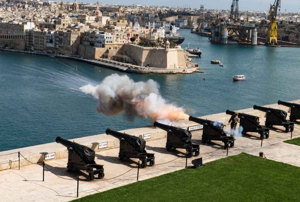 Valletta’s Saluting Battery firing a cannon over the Grand Harbour, Malta — historic view of the capital