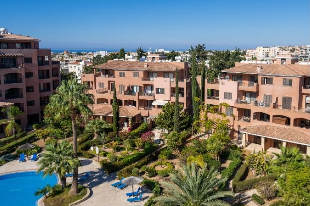 Cyprus travel guide Mediterranean-style apartment buildings in Paphos with gardens and a pool, popular for short-term stays.