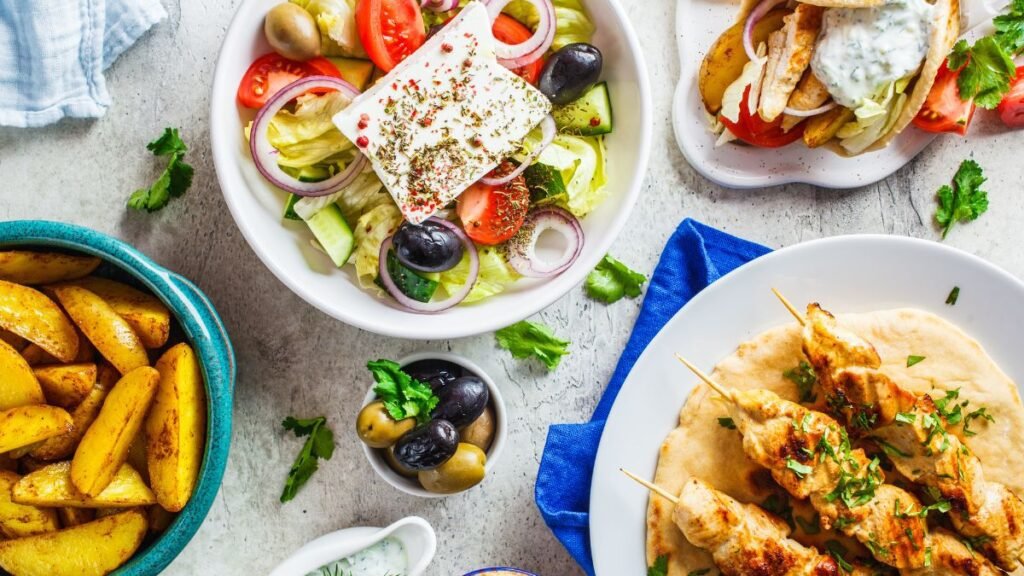 Greek salad with feta, olives, souvlaki skewers, and pita bread on a table