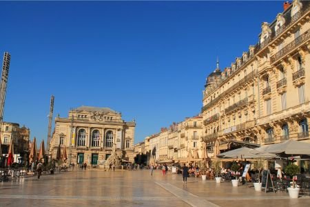 Sunny day at Place de la Comédie in Montpellier with historic buildings and open cafés.