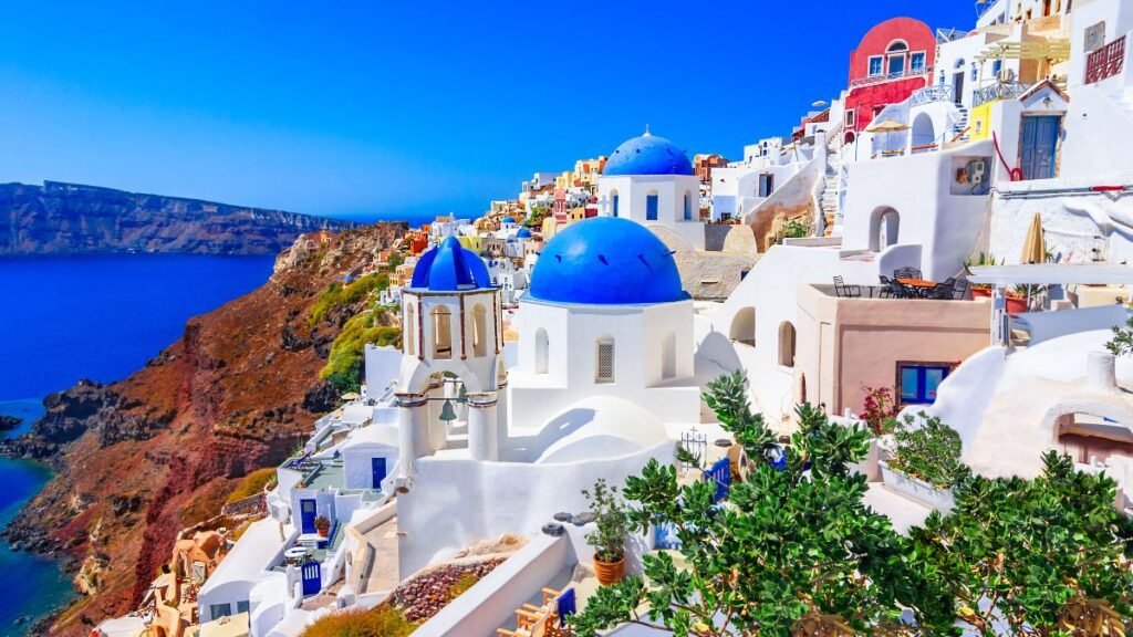 Retiring in Greece - Whitewashed buildings and blue-domed churches overlooking the caldera in Santorini, Greece